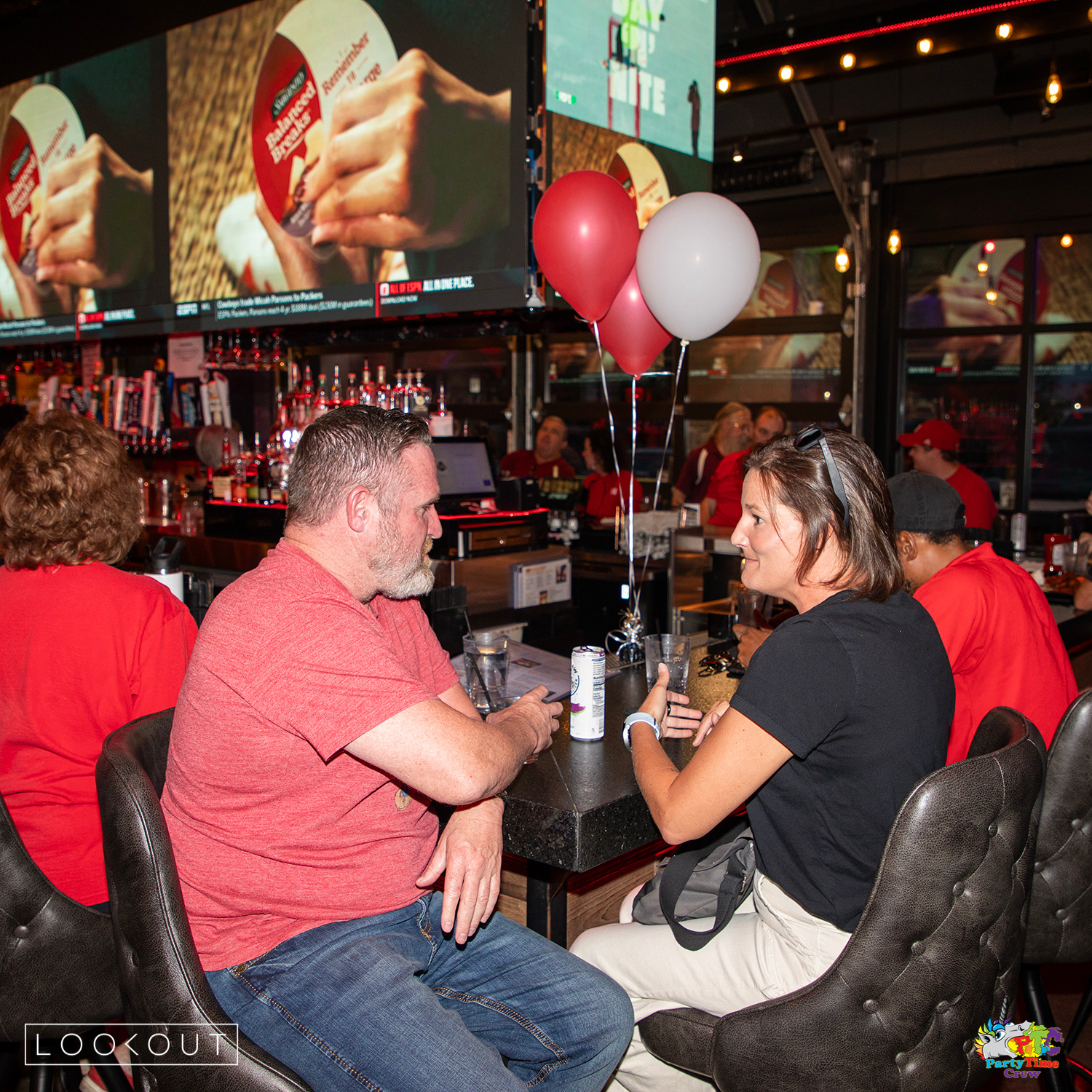 Fans talking over drinks under red and white balloons