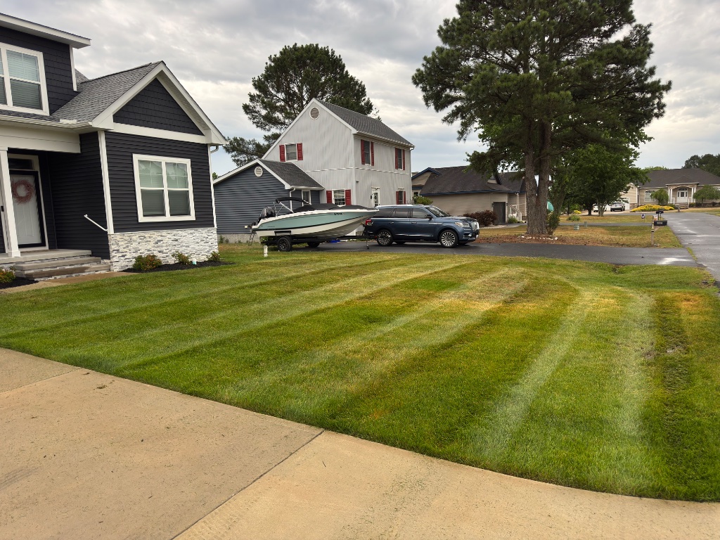 Driveway view of home with diagonal mowing stripes