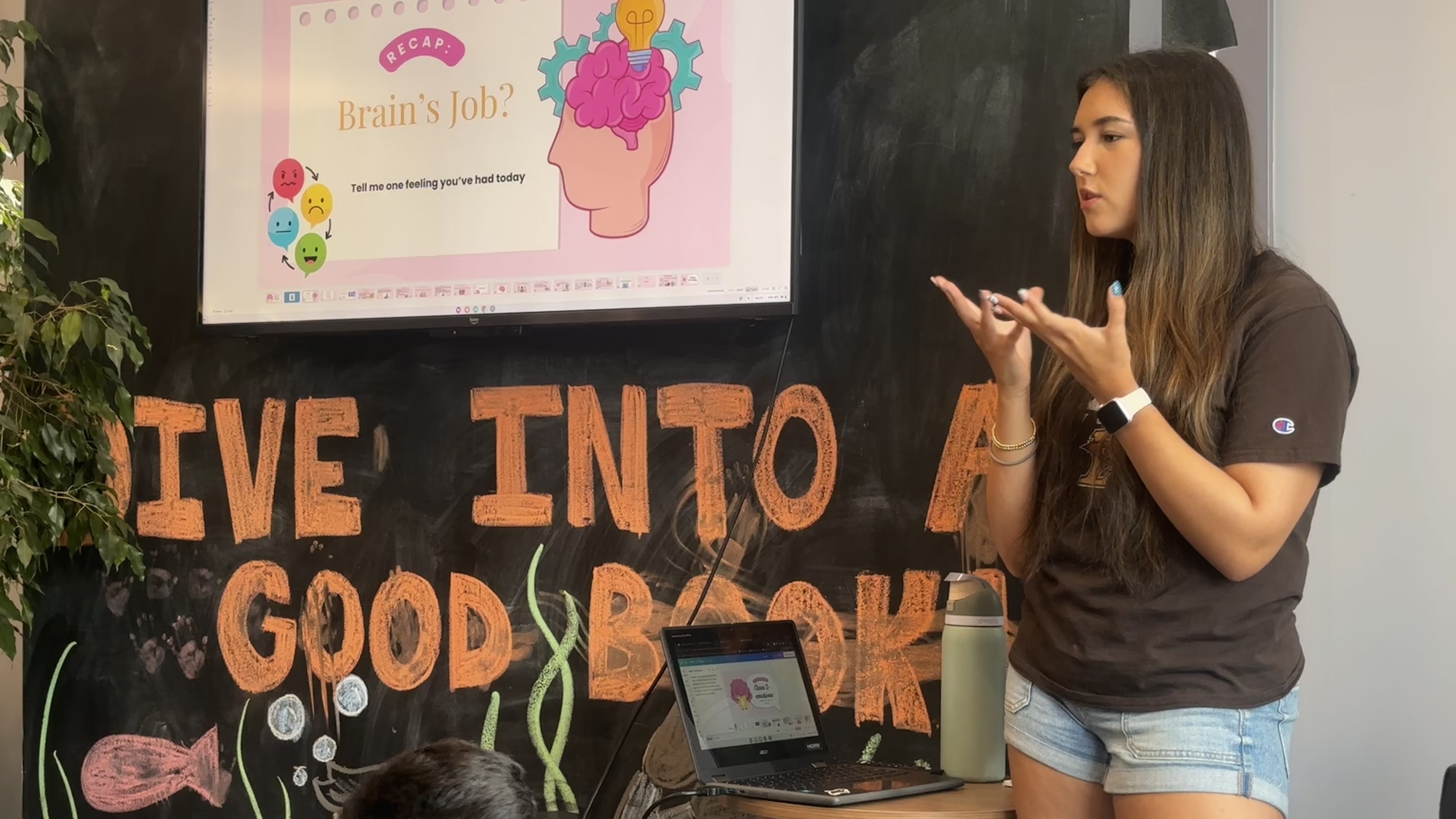 A lesson being explained at a library, slides on the screen and a laptop open on the table.