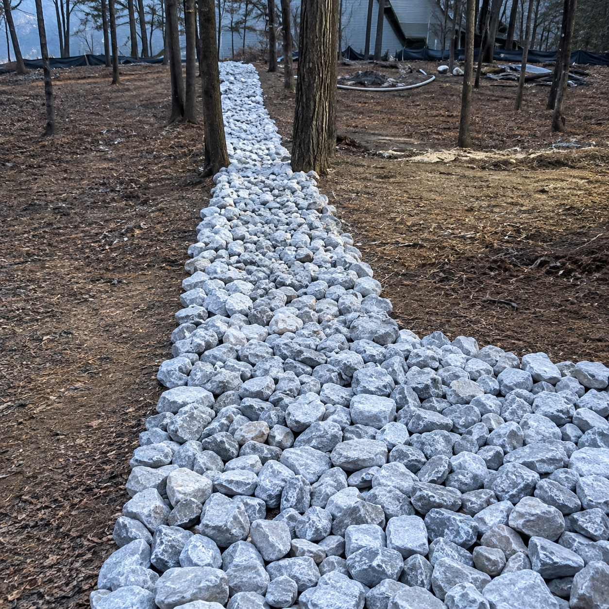Stone-lined swale channel carrying runoff through the woods
