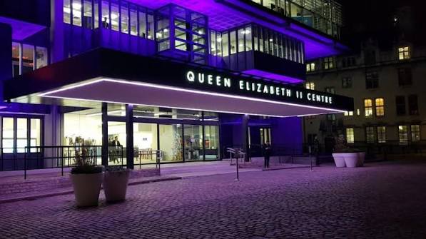 Queen Elizabeth II Centre entrance at night, lit in purple