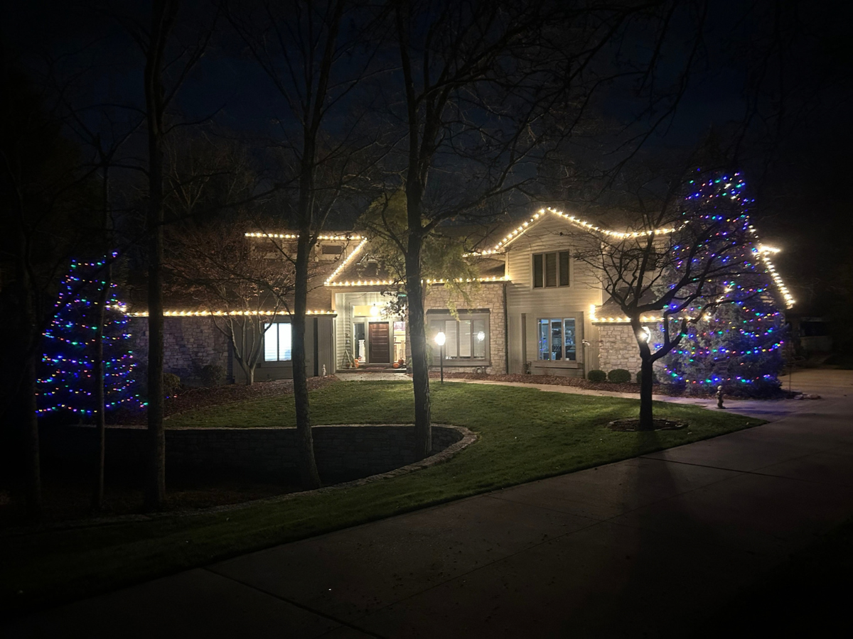 Multicolor Christmas lights on trees and Cincinnati home roofline