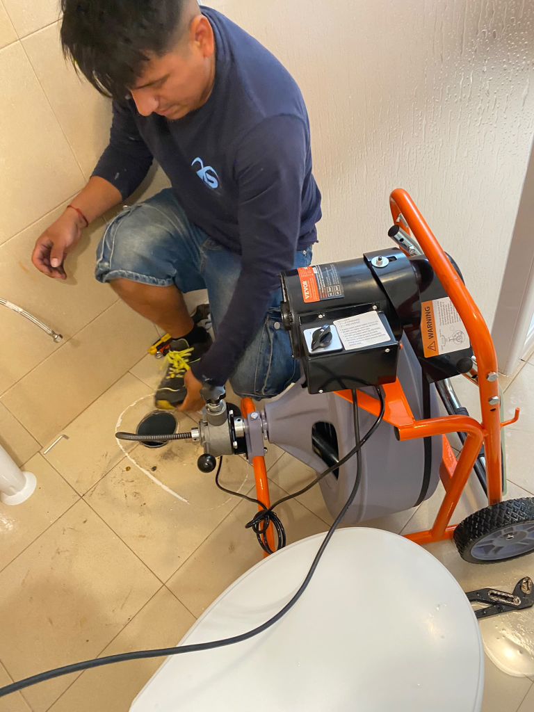Técnico de Ibiza Solutions con máquina de desatascos profesional junto al inodoro desmontado