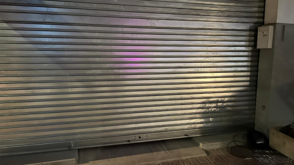 Detalle de la persiana comercial rota con daños estructurales