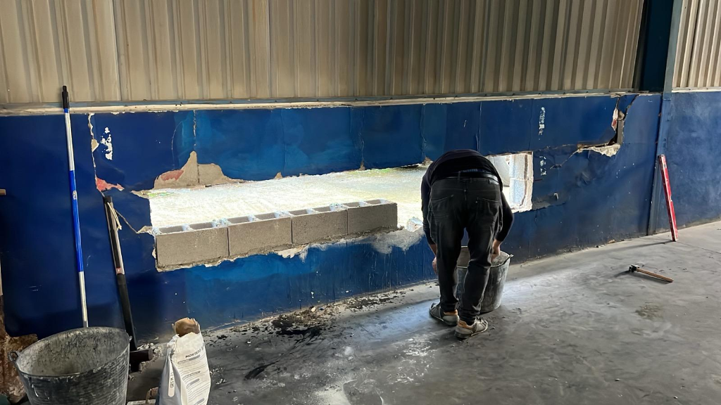 Pared de nave industrial de Salas Simó rota por accidente de camión, técnico reconstruyendo con bloques
