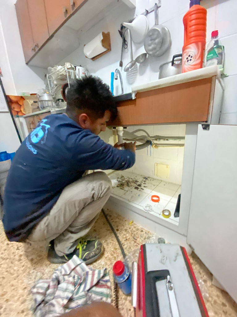 Técnico de Ibiza Solutions trabajando bajo el fregadero de la cocina