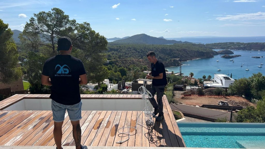 Técnicos de Ibiza Solutions en la cubierta de la villa con vistas a la bahía de Ibiza
