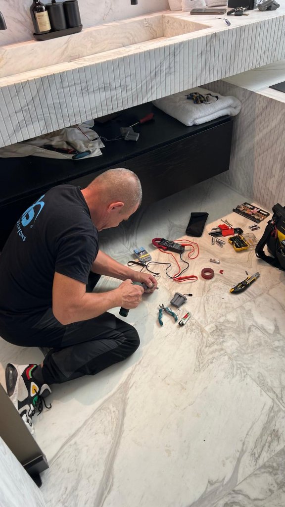 Técnico Ibiza Solutions realizando revisión eléctrica en el baño de mármol de la villa