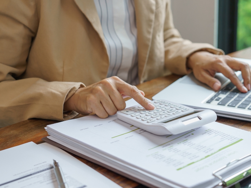 Person using calculator and laptop to review finances