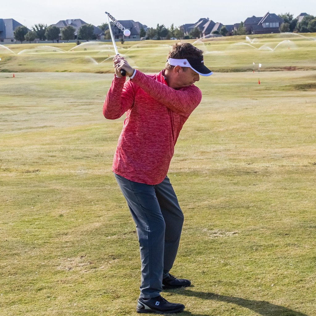 Golfer at the top of the backswing with the Swing Thing, chain planing with the shaft