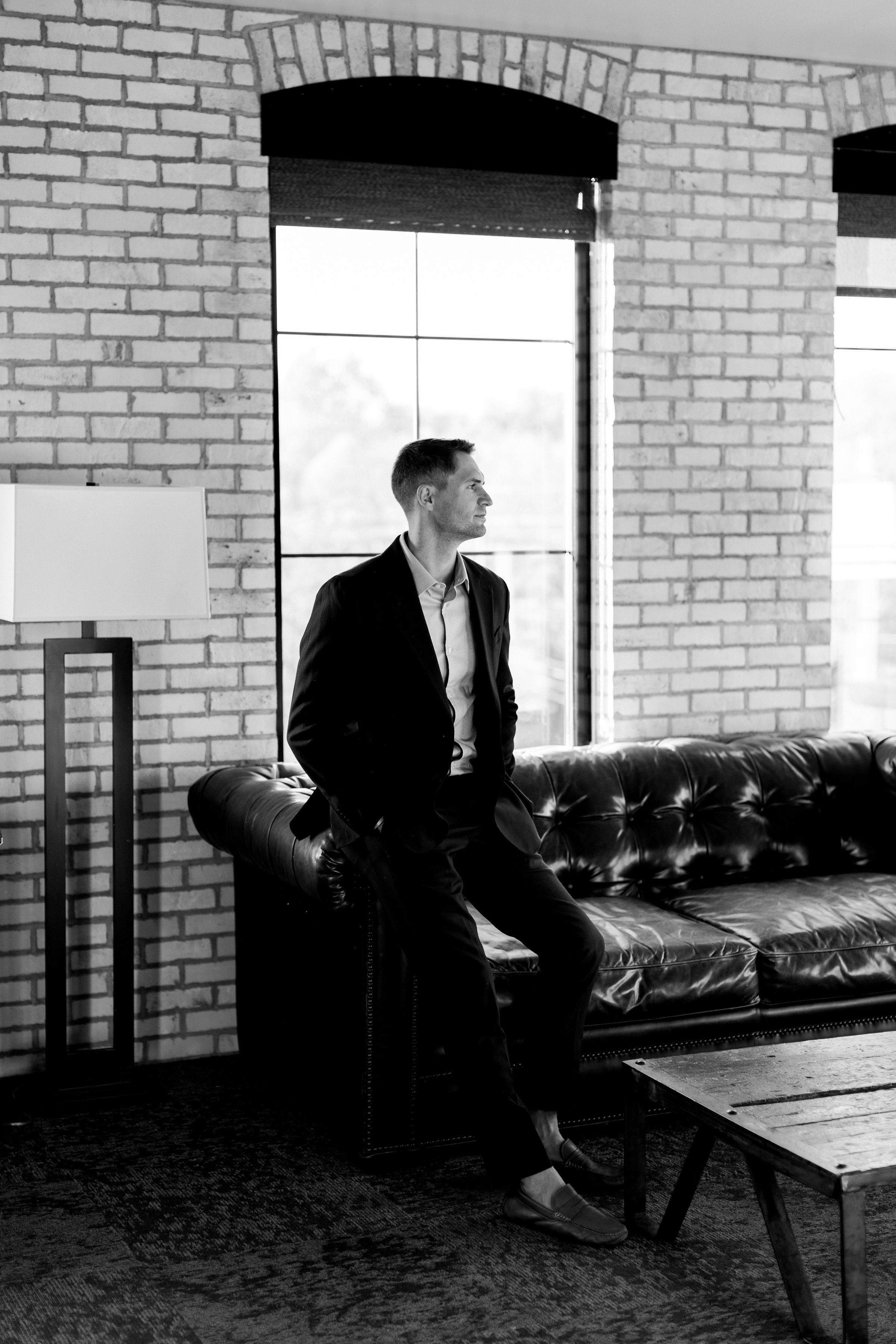 Man in a suit standing in a brick-walled room