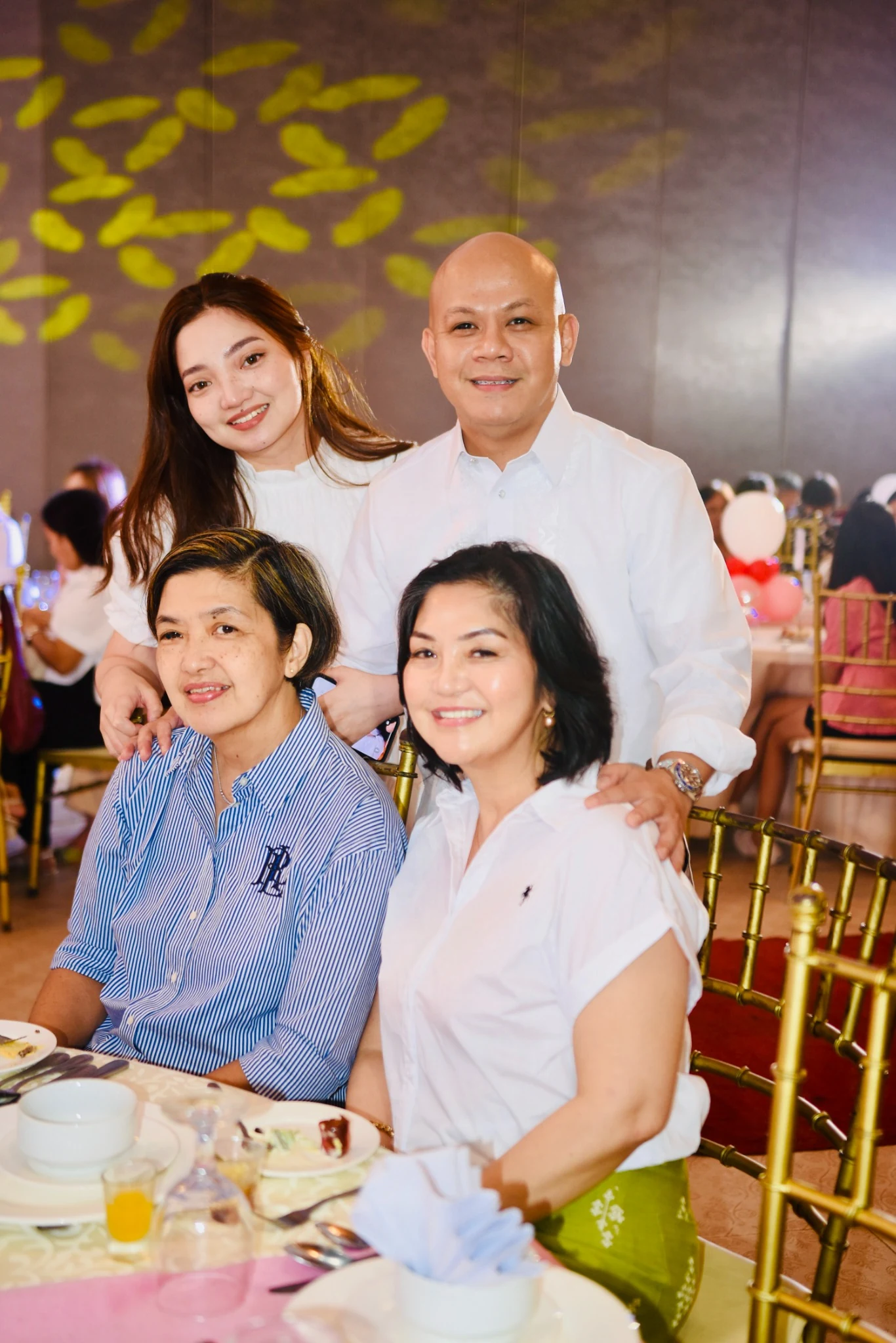 Four guests smile for a portrait beside the reception table.