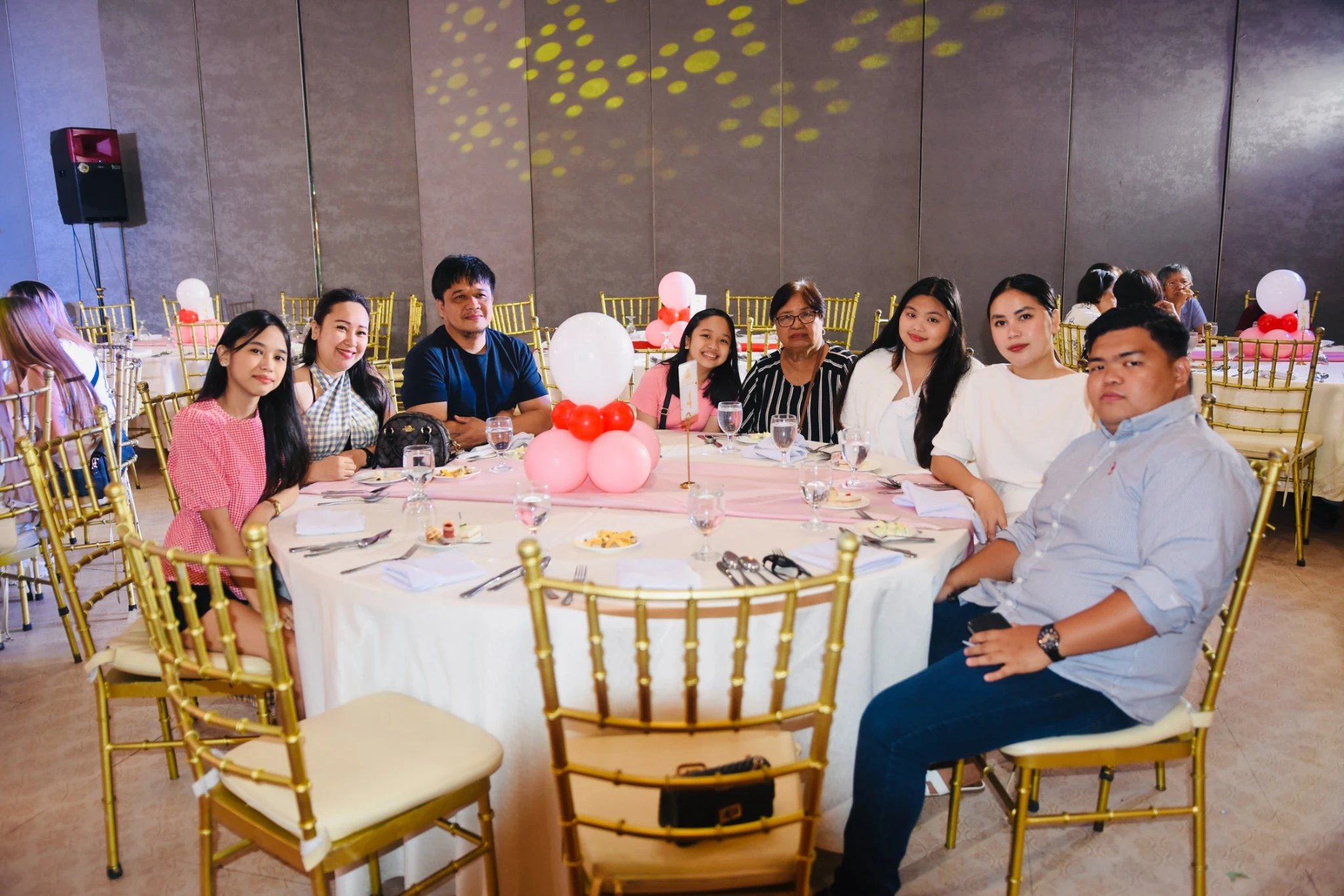 Guests gather around a table decorated with balloons.