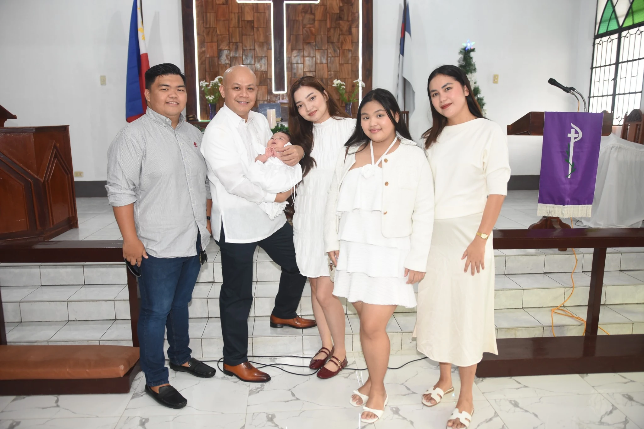 A group gathers with the baby for a photograph inside the church.