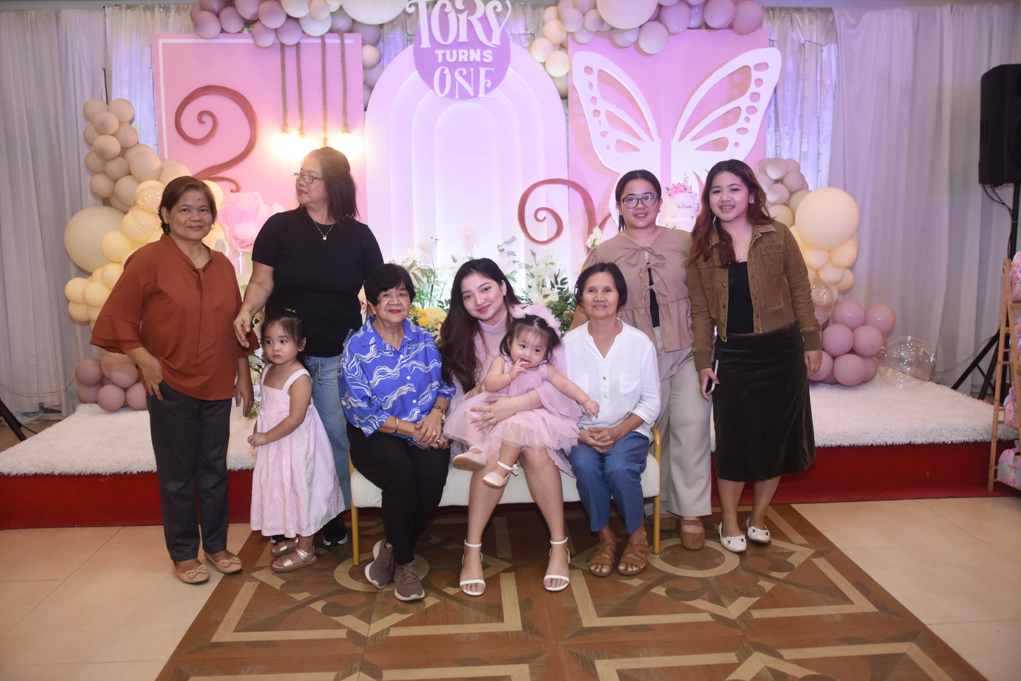 Another candid group portrait with the birthday child and guests against the pink and lilac decorations.