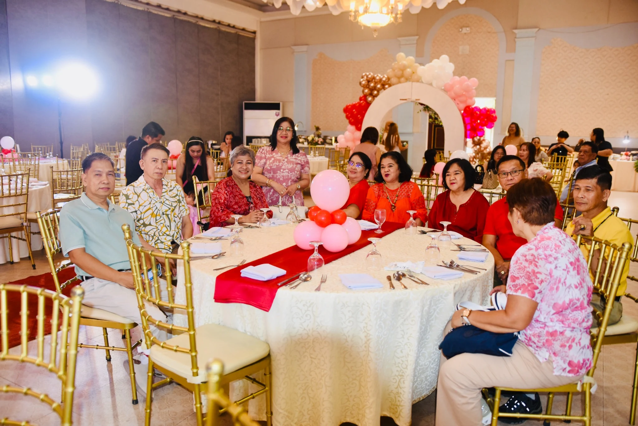 Guests seated around a reception table with red and pink decorations.