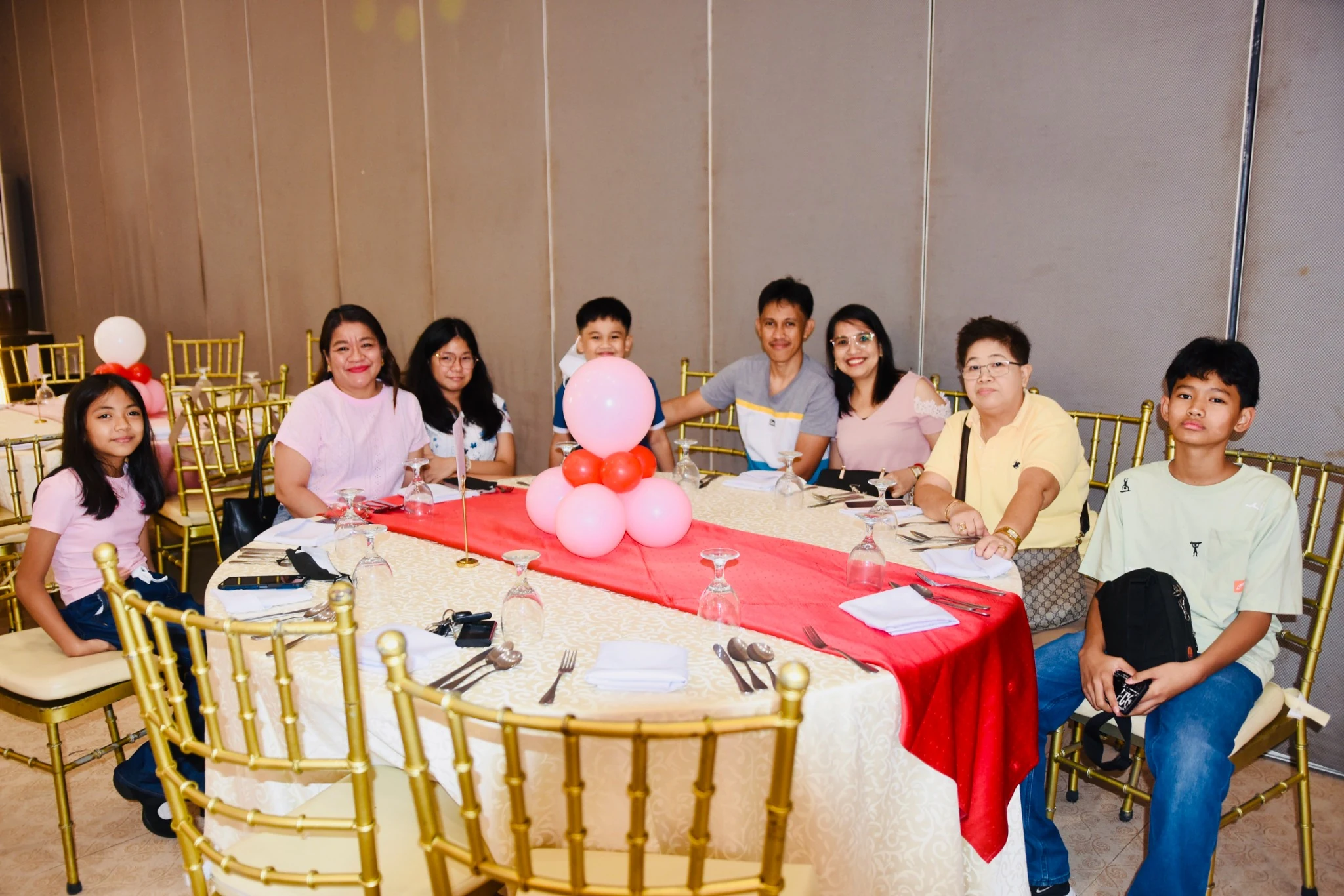 Adults and children smile together around a reception table.