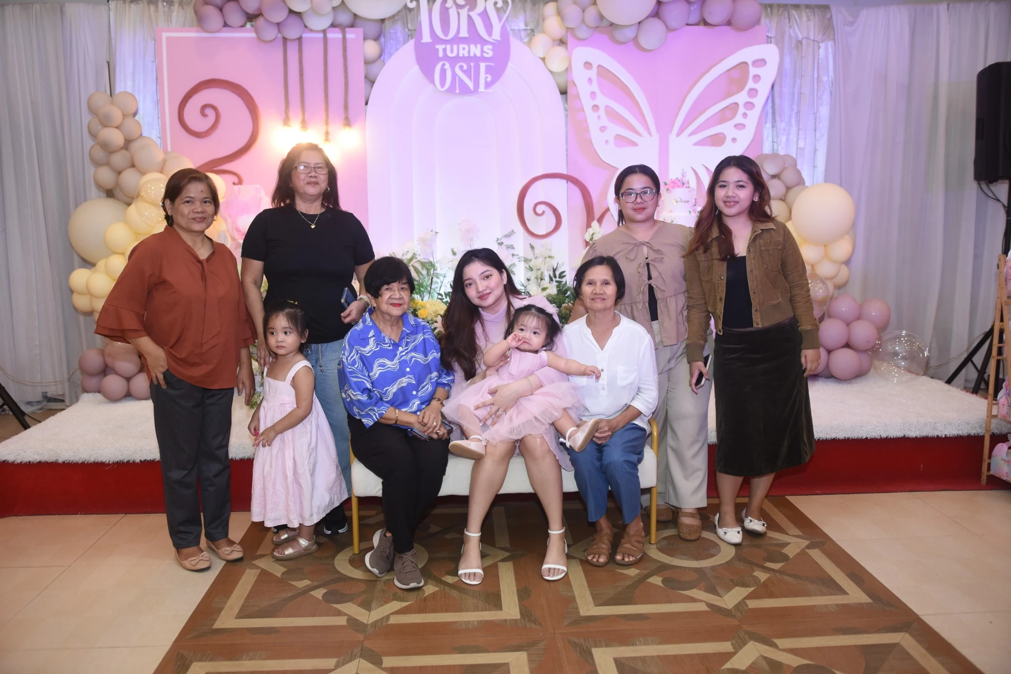 Guests and two children pose together in front of the birthday backdrop.