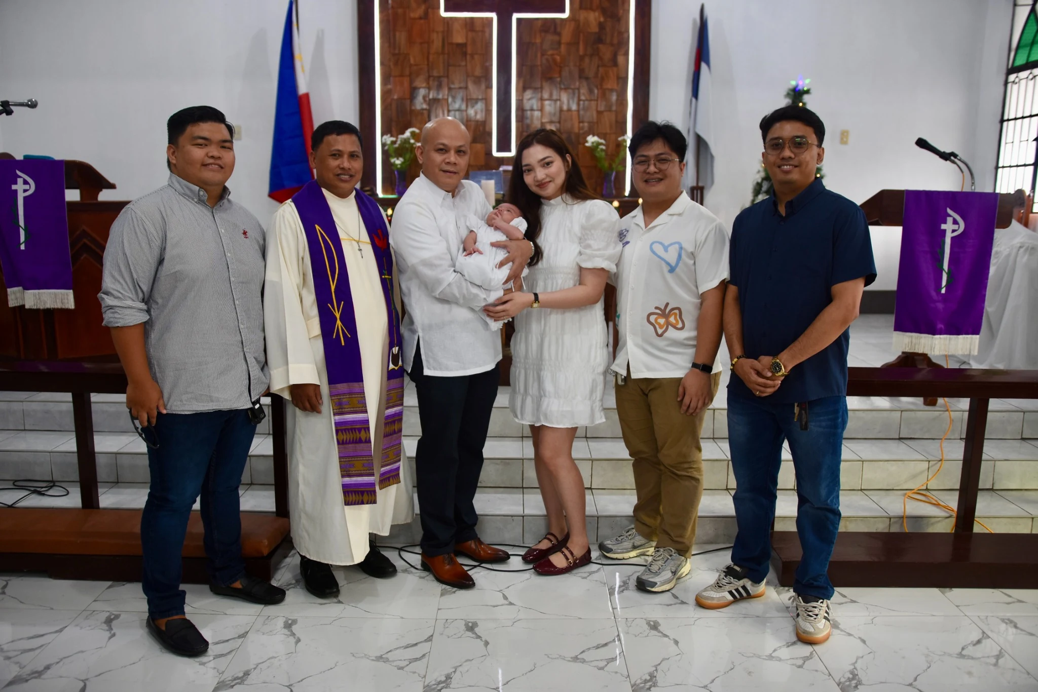 A group portrait in front of the church altar during the baptism celebration.