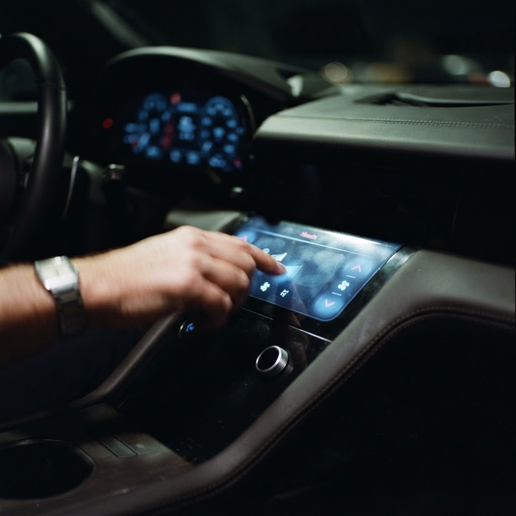 Illustration of A cinematic close up of a luxury car dashboard in darkness, glowing soft blue haptic zones highlighting physical touch points on a glass interface, high tech, futuristic, sharp focus, professional automotive photography. - Haptic Zones Technology
