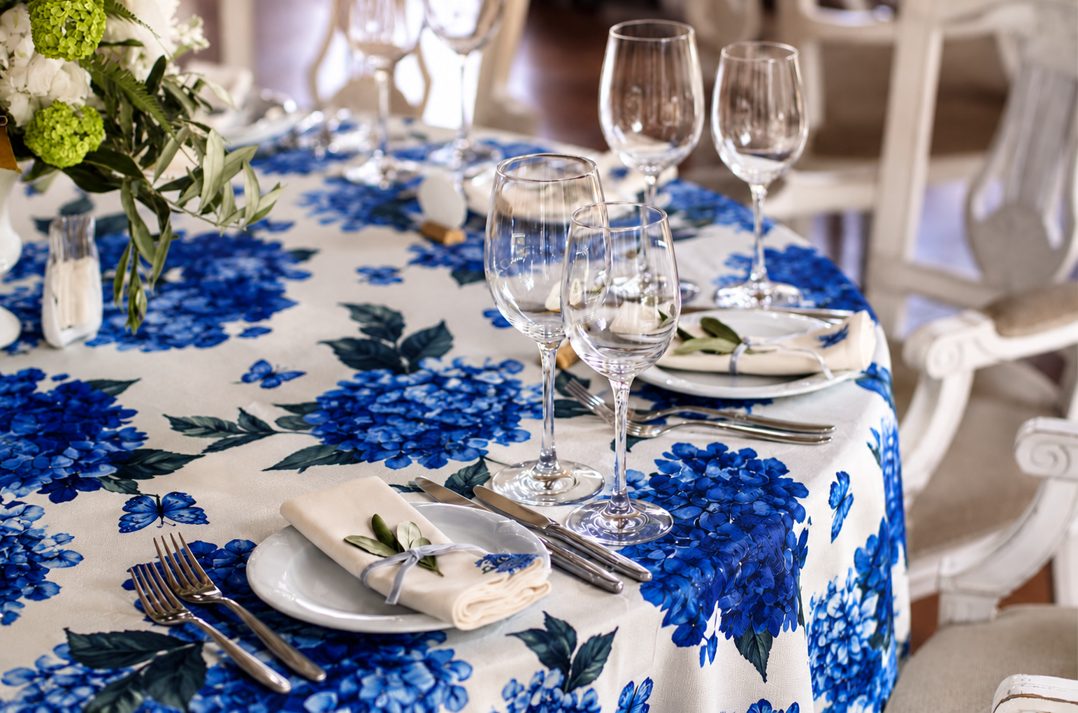Wedding table setting with blue floral printed linen, glassware and white napkins