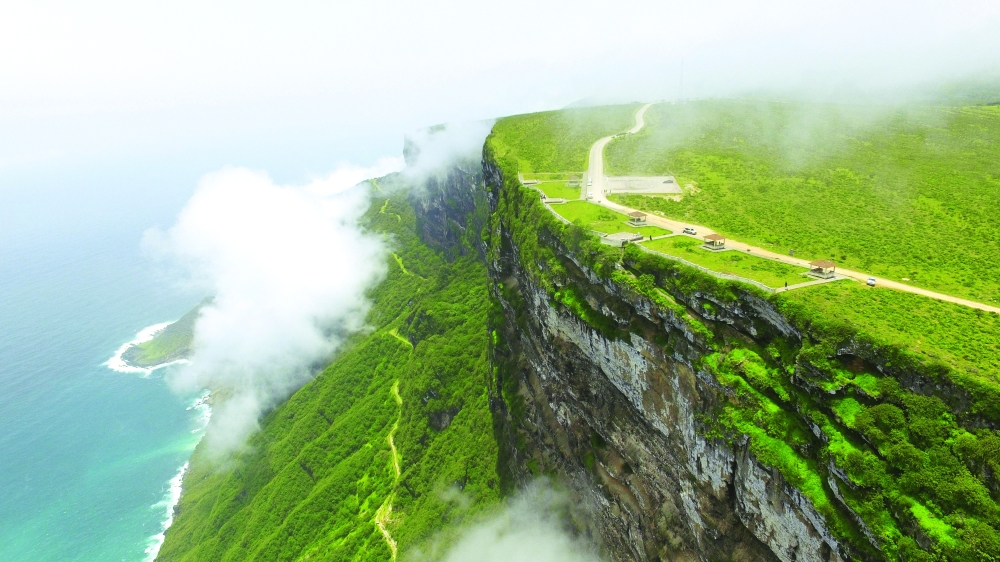 Cars driving on scenic winding mountain road in Salalah during Khareef