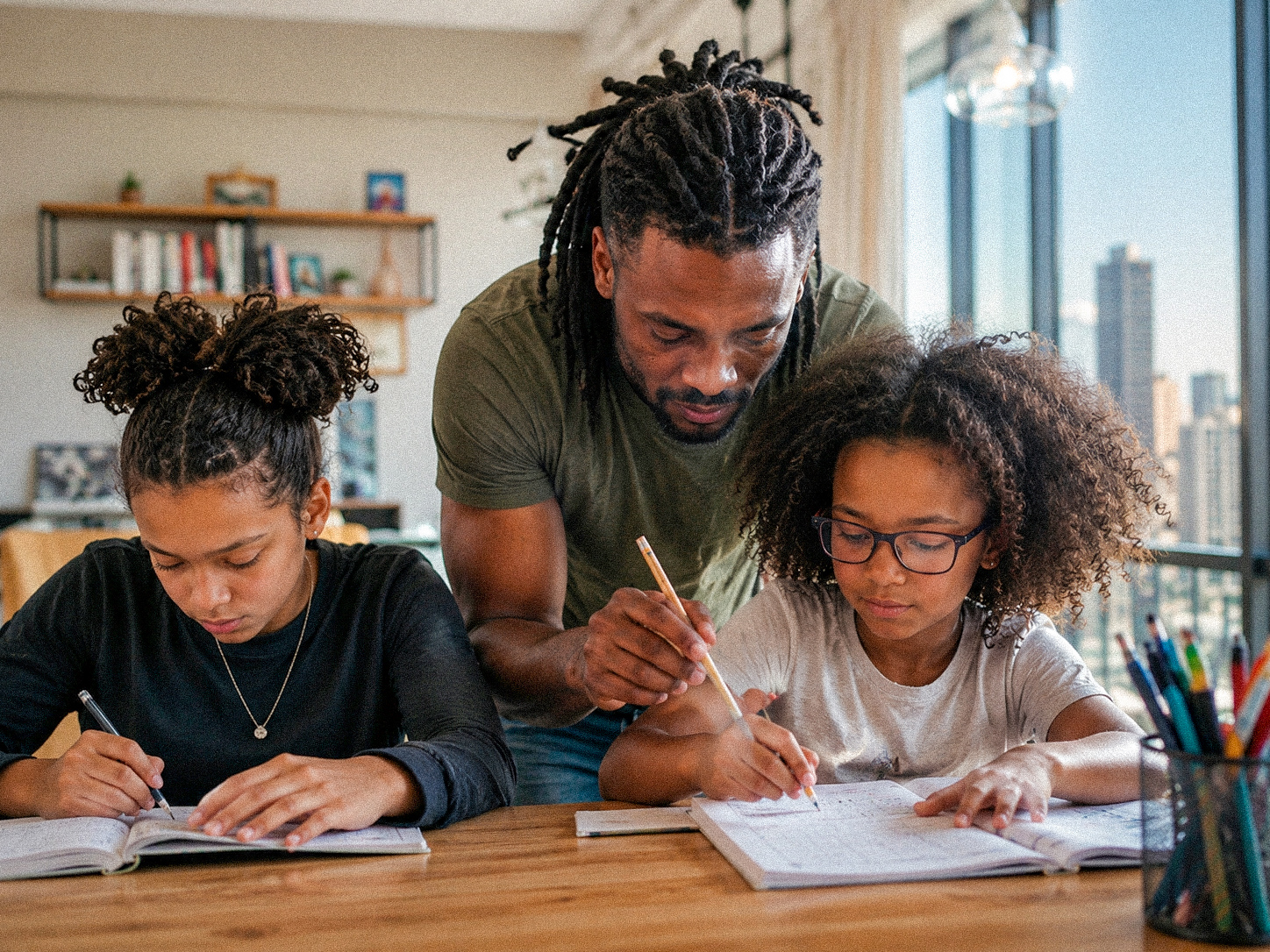 A father guiding his daughters through schoolwork at home
