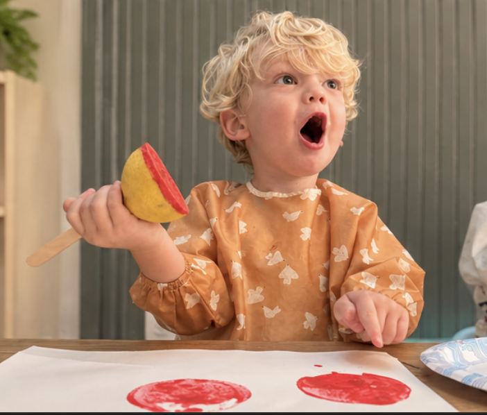 Child painting with citrus fruit at Casita Kids