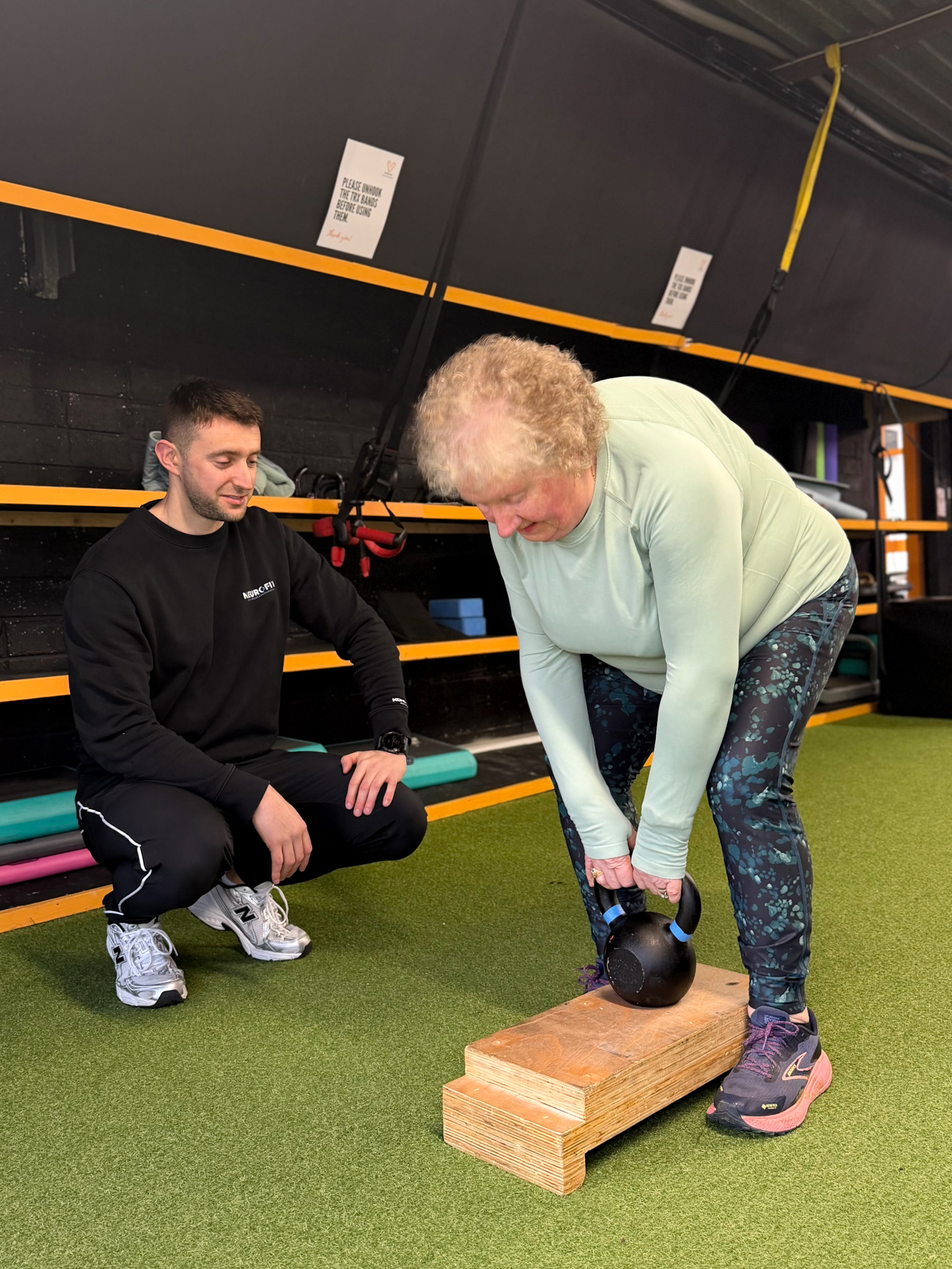 Trainer coaching an older adult through a strength exercise