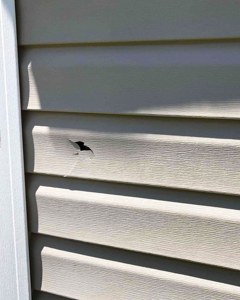 Hail damage on vinyl siding with dozens of impact dents