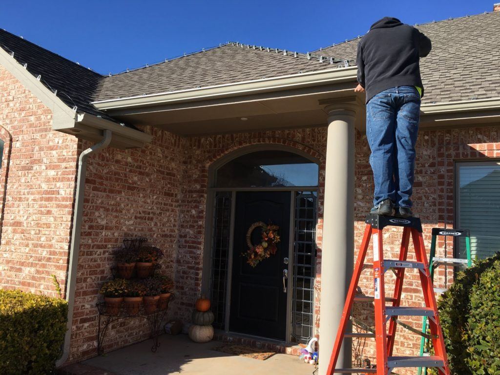 Blue Martin crew member installing gutters on ladder