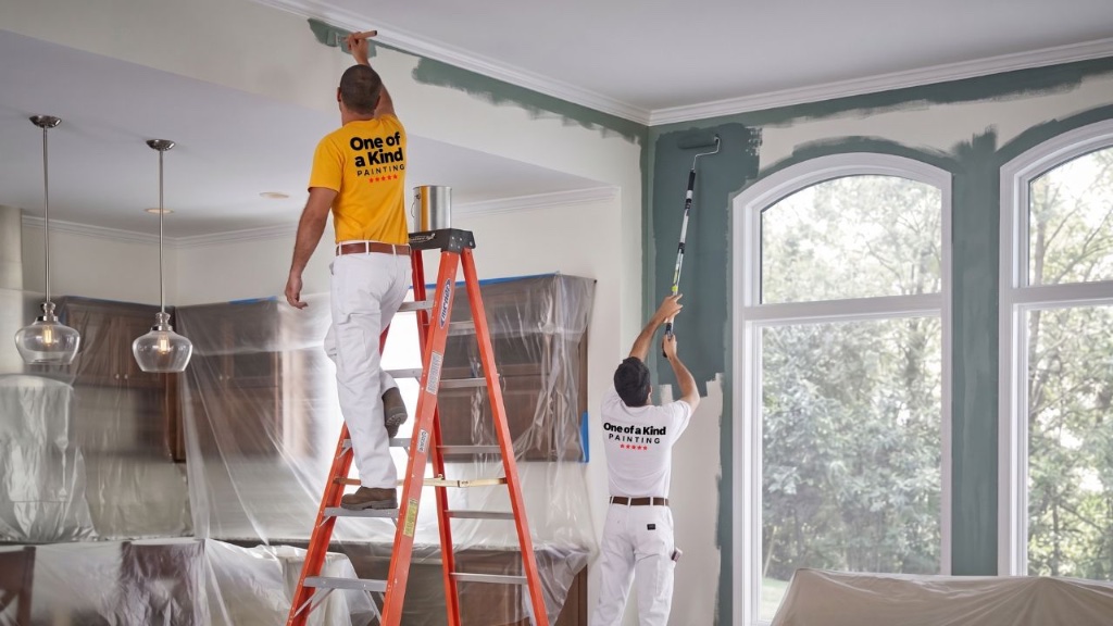Painters on ladders painting an interior room