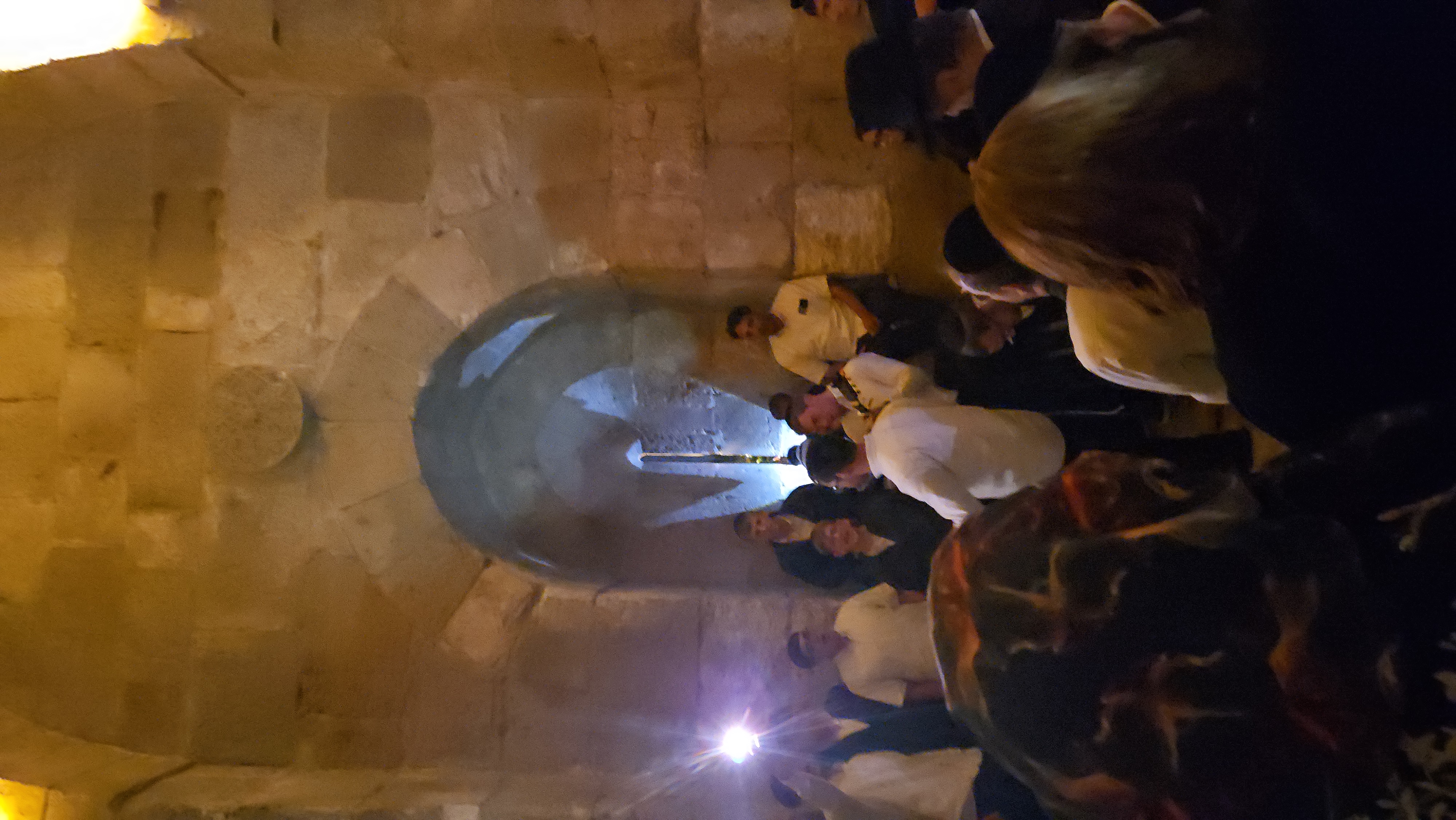 Twenty men squeeze into a vault older than their grandfathers, and someone turns on a phone light so the singing can find its page. This is a Tuesday here.