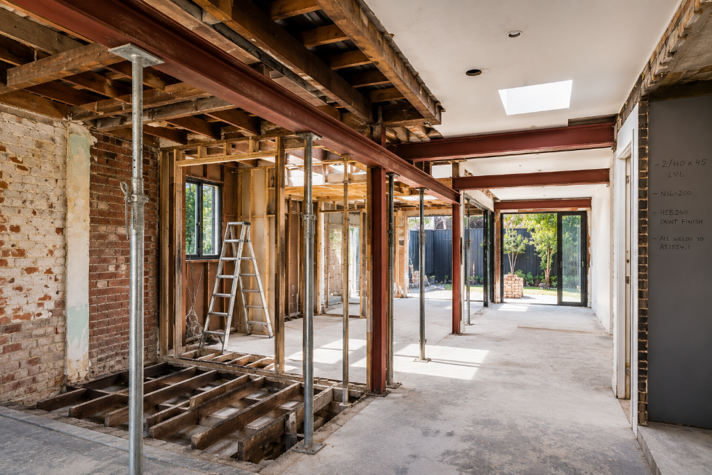 Major structural home renovation in Melbourne featuring exposed structural steel beams, temporary propping, wall removal, floor framing modifications and engineered building alterations completed by Brownlow Building.