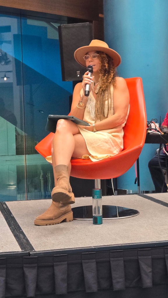 Diana seated on stage with microphone