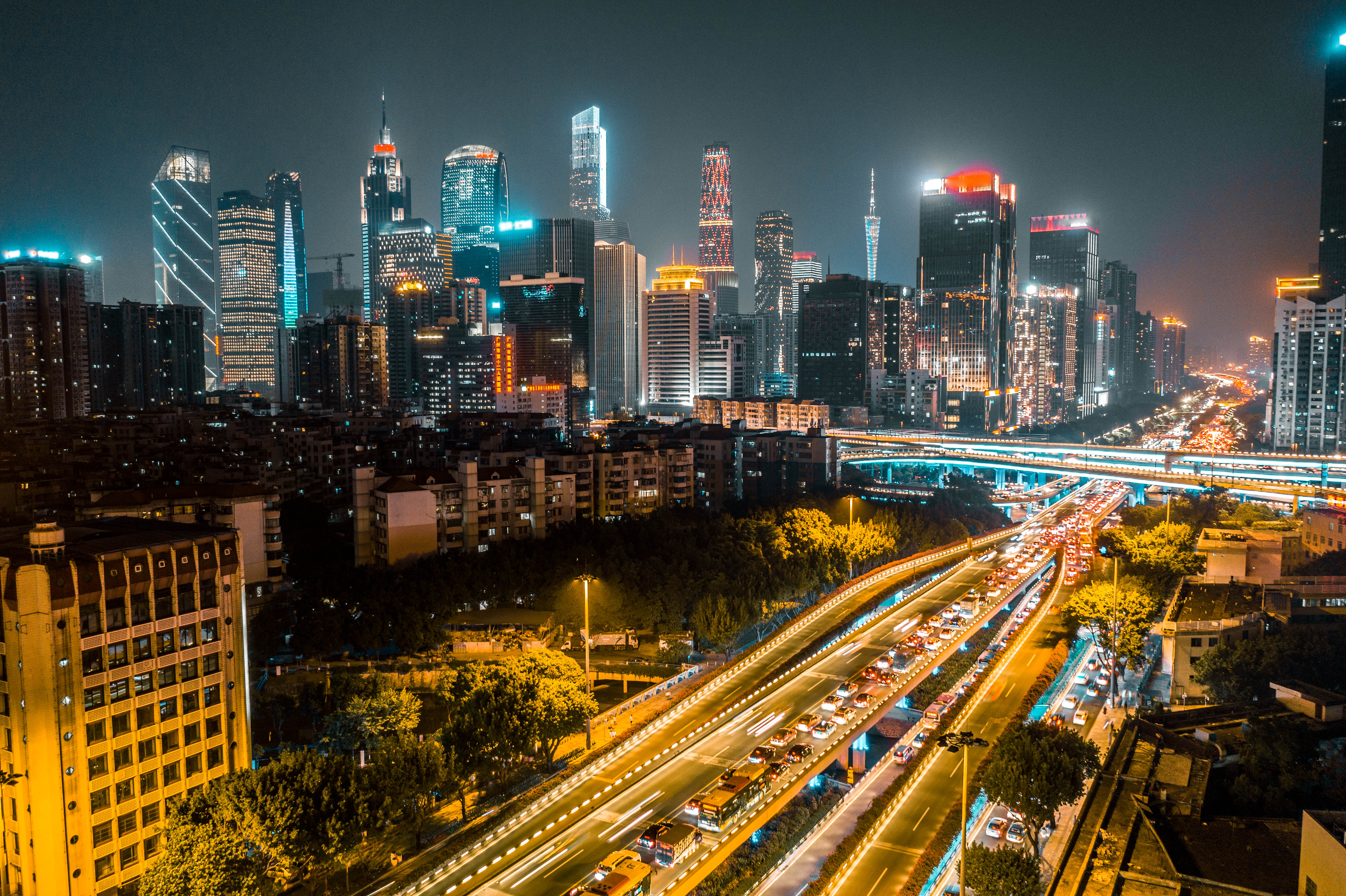 Night city skyline with lit expressways full of moving traffic.