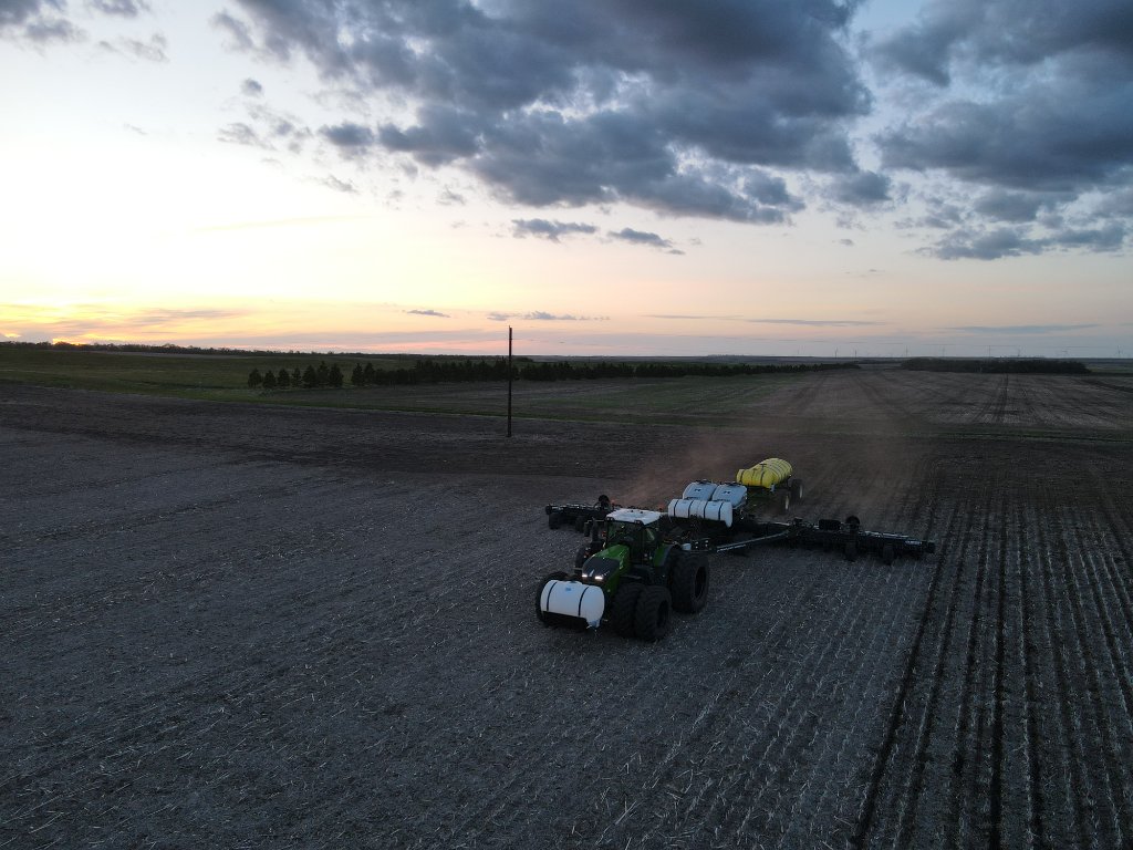 Aerial drone view of tractor planting at sunset