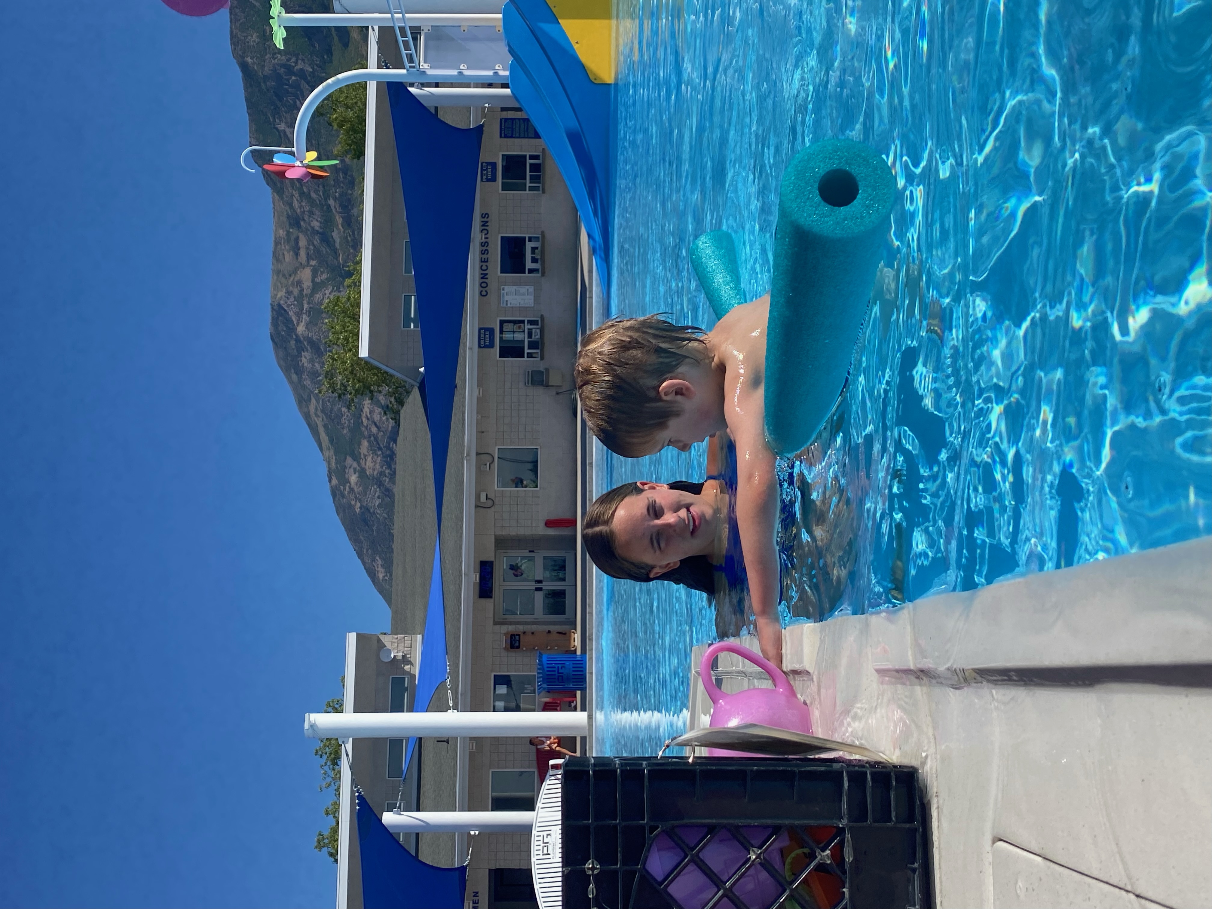 Adaptive instructor supporting a child with a pool noodle