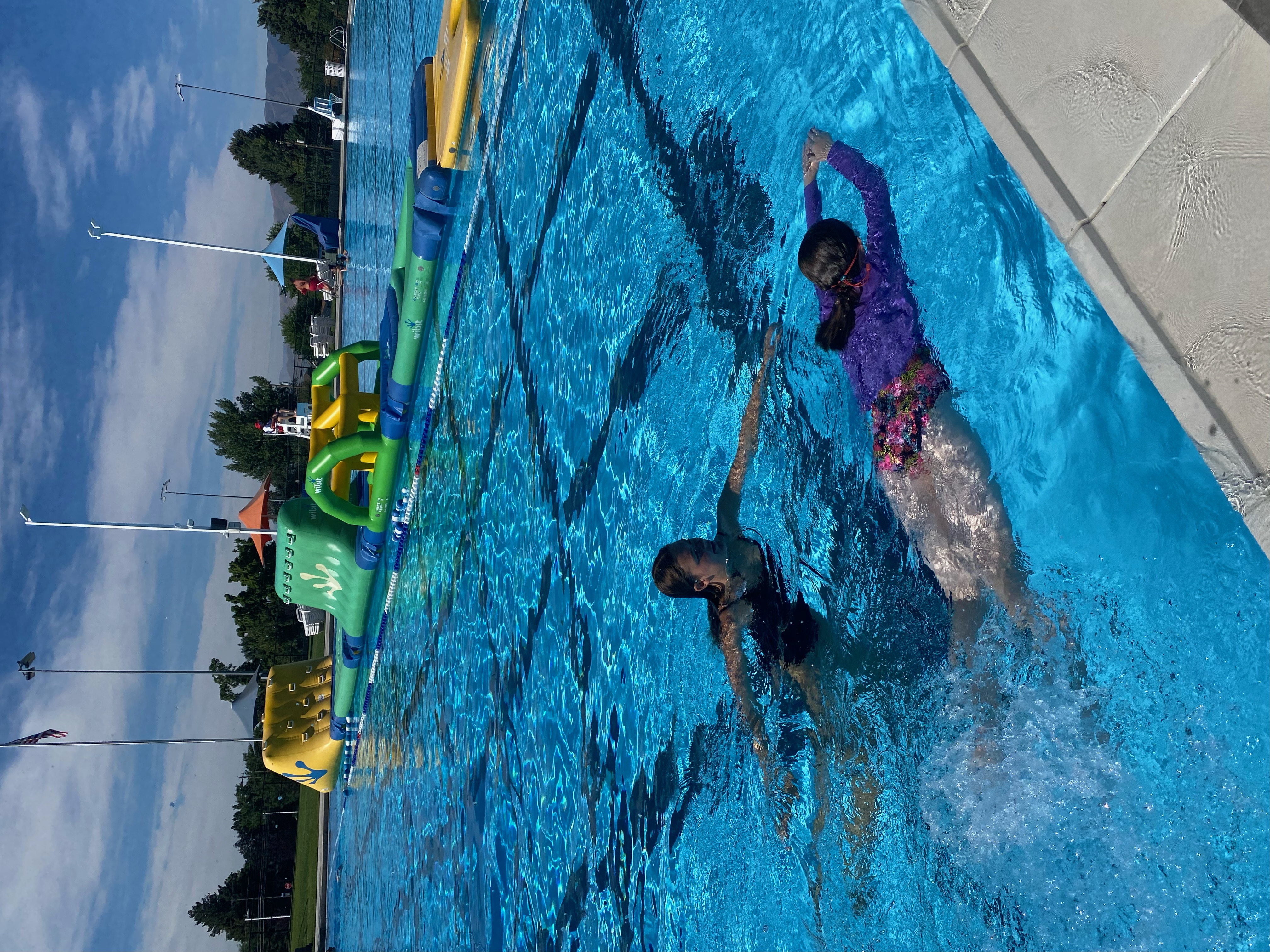 Swimmer practicing on their back with instructor support