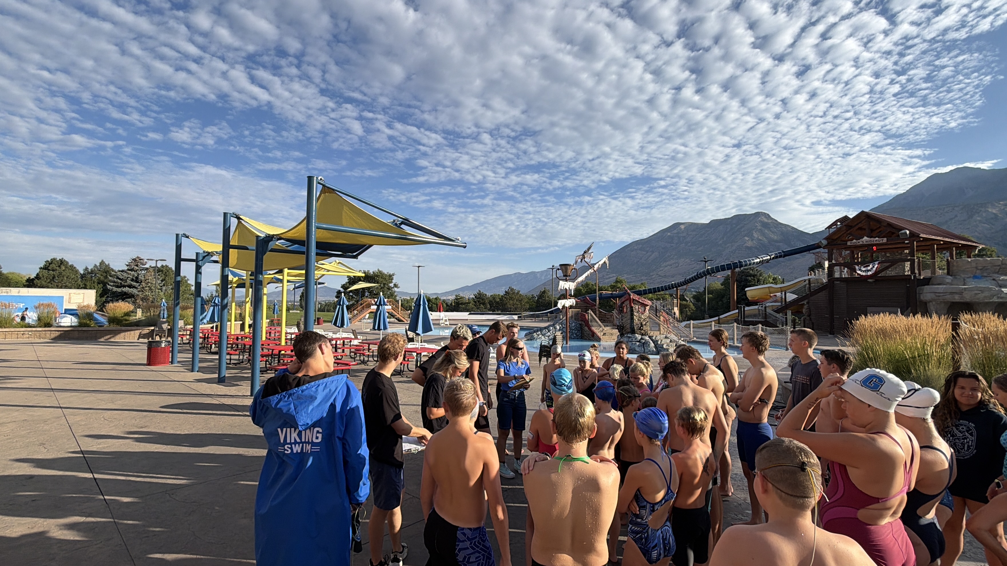 Swim team gathering with coach on the pool deck