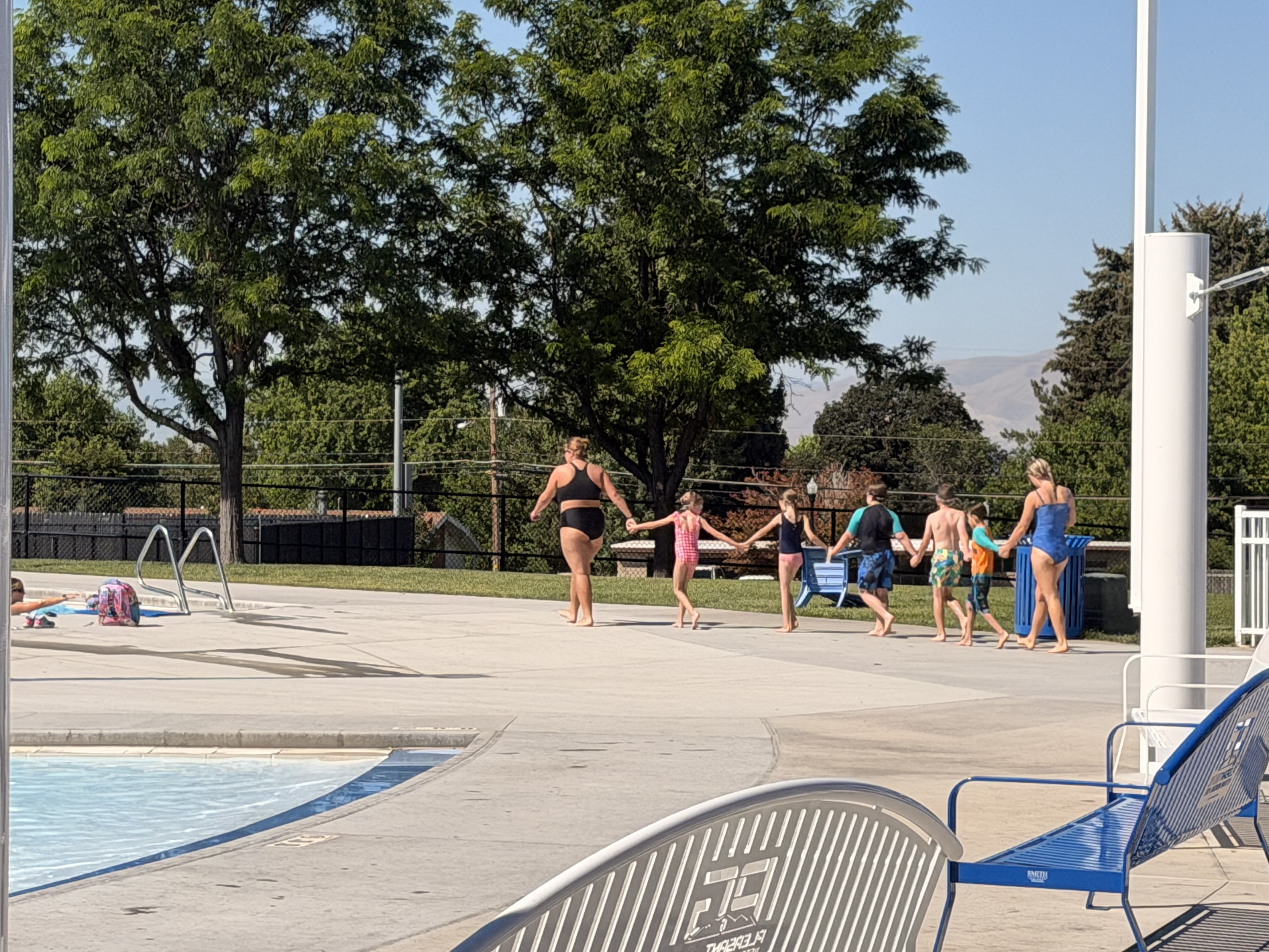 Group holding hands walking along the pool deck