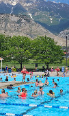 Pool full of swimmers with mountains in the background
