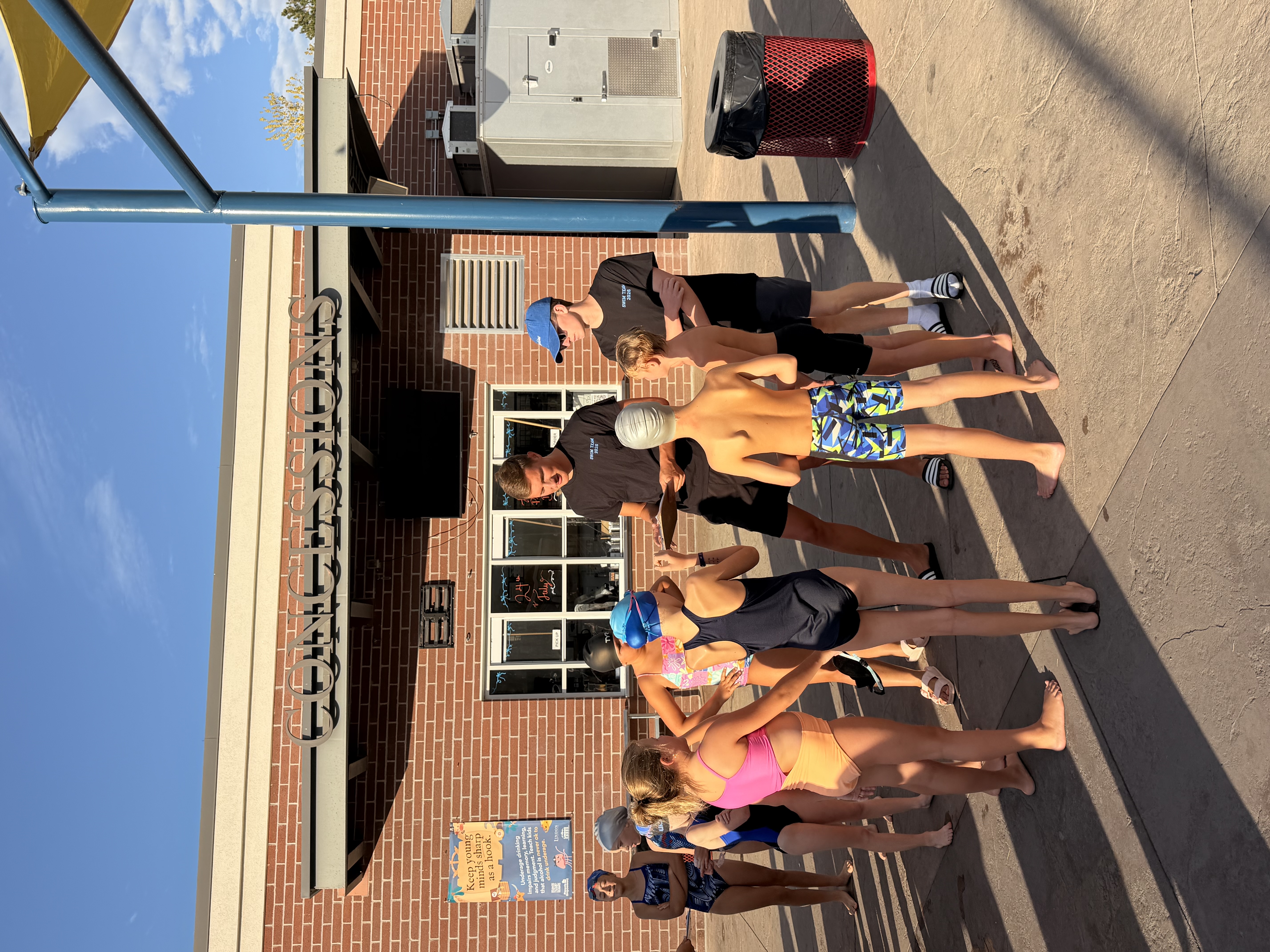 Swim team swimmers lined up by the concessions building