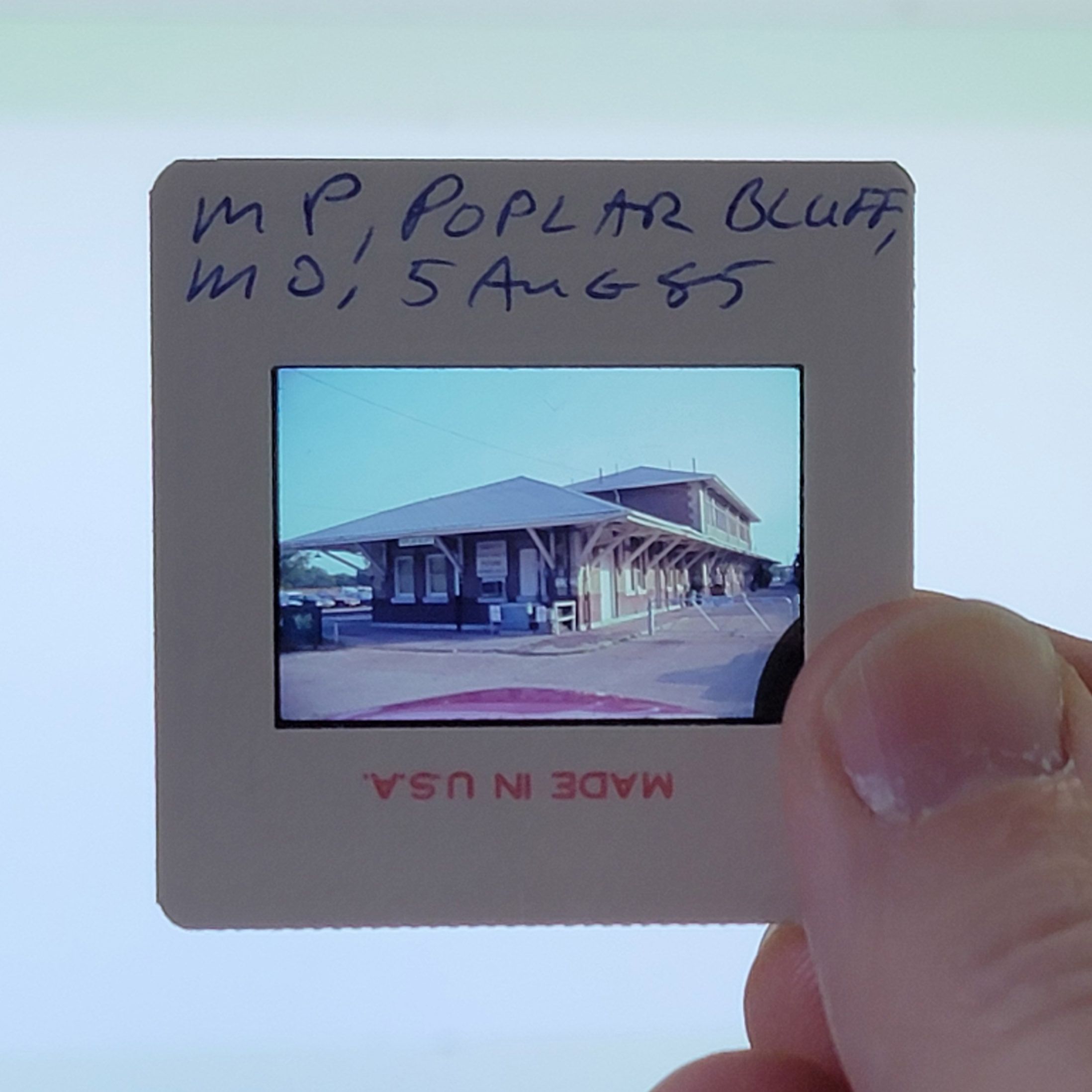 Slide mount showing handwritten provenance: 'MP / POPLAR BLUFF, MO / 5 AUG 85' in blue ink, with 'MADE IN U.S.A.' printed in red on the bottom edge (inverted).