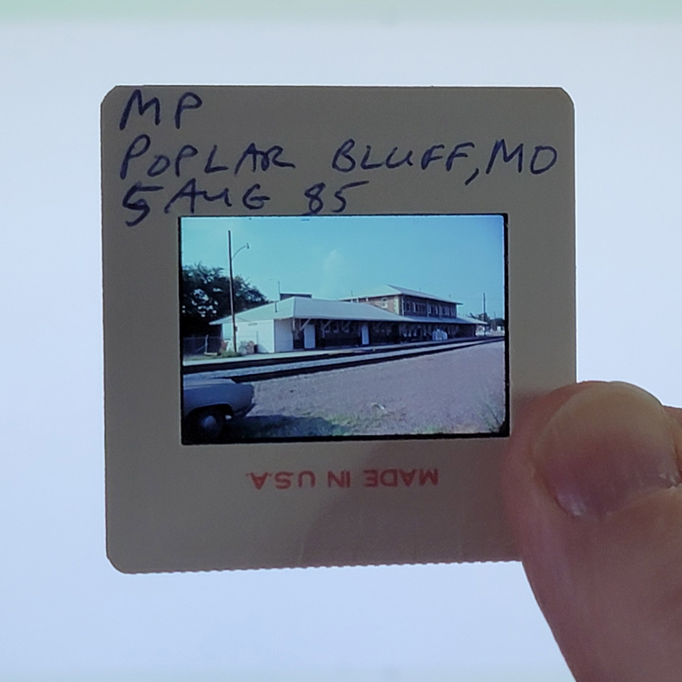 Slide mount showing handwritten provenance: 'MP / POPLAR BLUFF, MO / 5 AUG 85' in blue ink, with 'MADE IN U.S.A.' printed in red on the bottom edge (inverted).