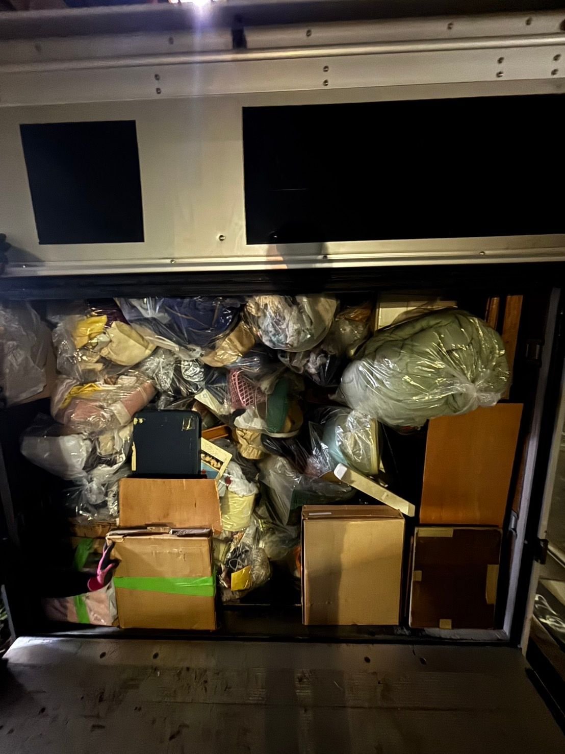 箱型トラックの荷台いっぱいに積んだ袋詰めの荷物と段ボール箱