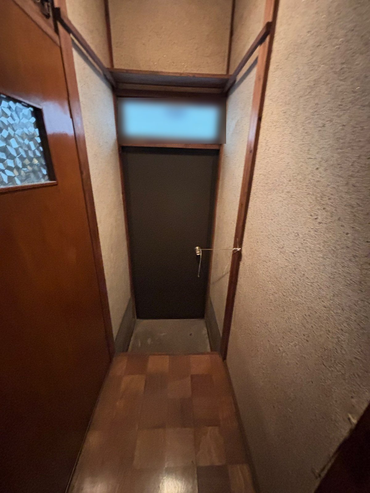 家財を運び出した後の細い廊下。突き当たりに扉があり、床には何も残っていない