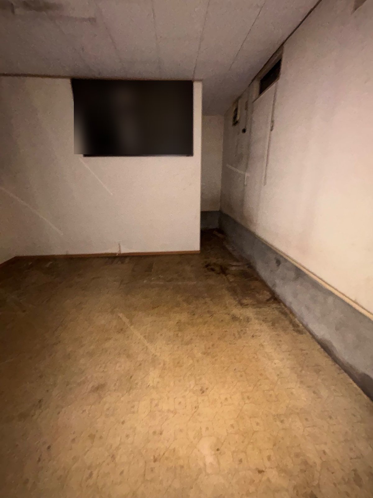 家財を運び出した後の部屋。壁に室内窓があり、床に物はないが、しみや汚れが残っている
