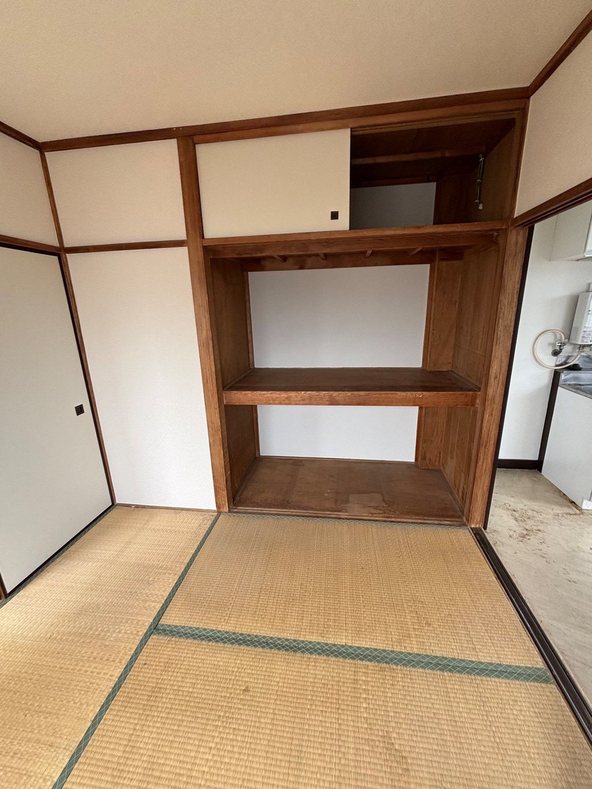 作業後の2階の和室。ふすまのない押入れと天袋が空になり、畳が見えている。右手に台所が続いている