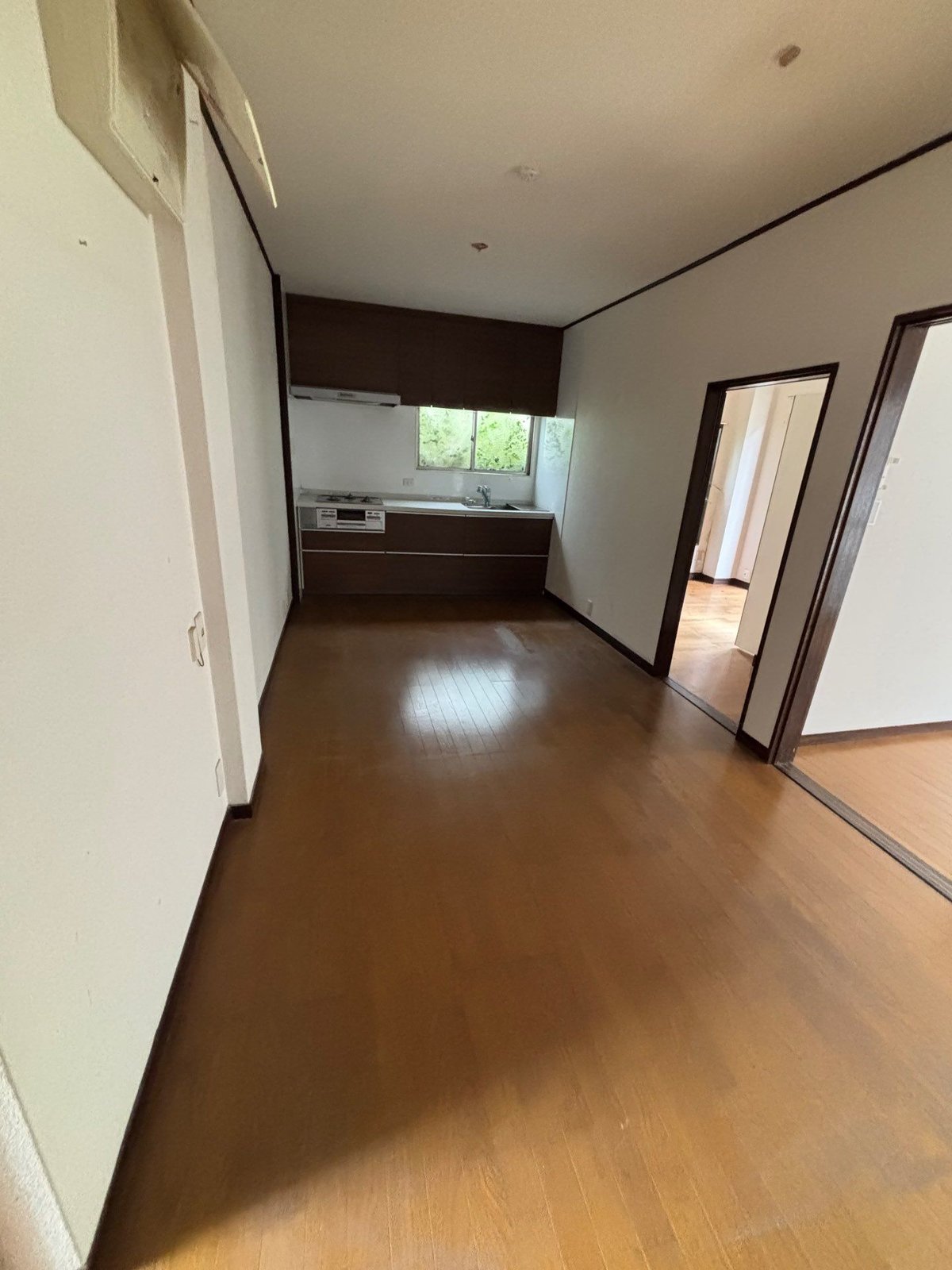 作業後の1階の住戸。突き当たりに台所があるフローリングの部屋で、床に物は残っていない。右手の2つの出入口から隣の部屋に続いている